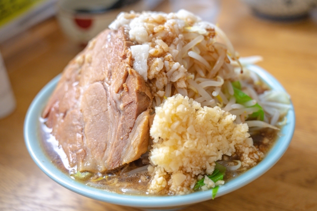 A bowl of Jiro-style ramen with thick, rich broth, topped with a generous portion of pork, bean sprouts, and minced garlic