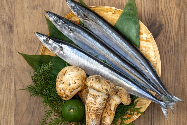 Fresh Pacific saury and Matsutake mushrooms displayed on a bamboo tray