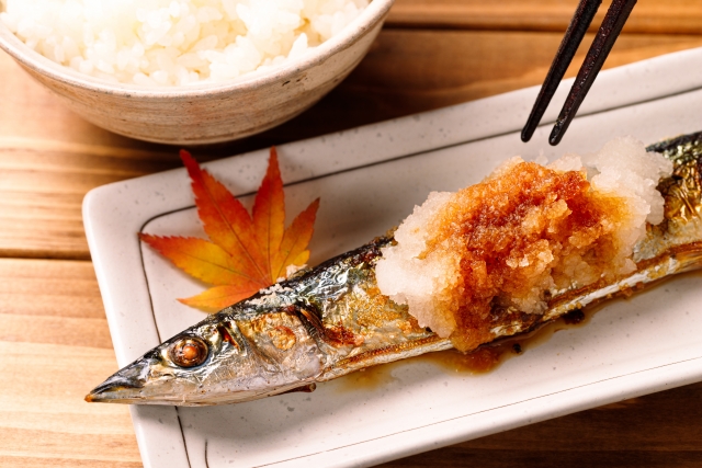 Grilled Sanma topped with grated daikon radish and soy sauce, served on a traditional Japanese plate