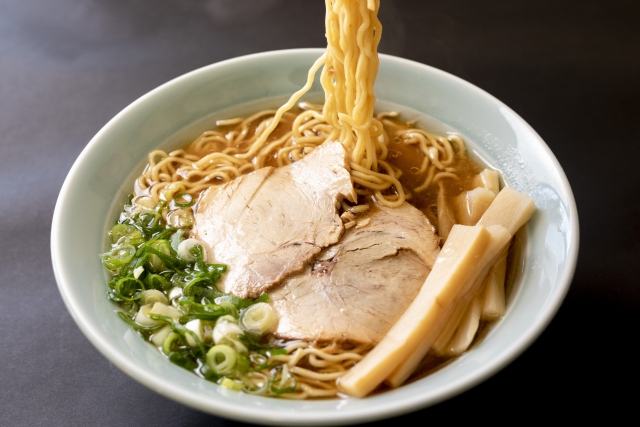 A bowl of shoyu ramen with a savory soy sauce-based broth, topped with slices of pork, green onions, and bamboo shoots