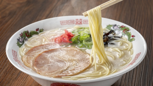 A bowl of traditional Tonkotsu ramen with tender slices of pork, green onions, and pickled ginger