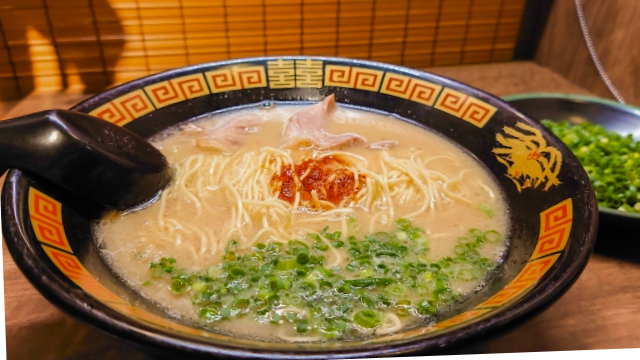 A bowl of Ichiran ramen featuring a rich tonkotsu broth, thin noodles, slices of pork, and a dollop of their signature spicy red sauce